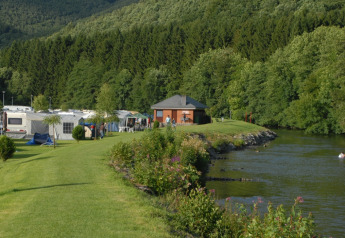 Safarizelt und Wohnwagen am Flussufer mit Wald im Hintergrund, Campingplatz Floreal La Roche-en-Ardenne.
