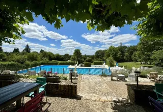 Uitzicht op zwembad en groen bij Camping Lestaubiere, vakantiepark in Nouvelle-Aquitaine, Frankrijk.