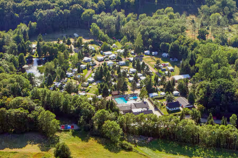 Aerial view of Skovly Camping holiday park in Region Zealand, Denmark, with caravans and lush green trees.