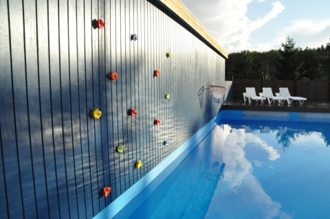 Klatrevæg ved siden af swimmingpool på Skovly Camping i Region Sjælland, Danmark med liggestole.