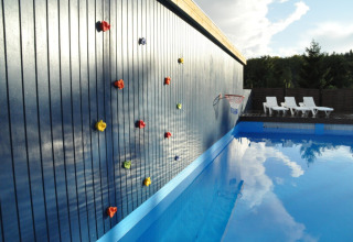 Klatrevæg ved siden af swimmingpool på Skovly Camping i Region Sjælland, Danmark med liggestole.