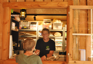 Personne servant un client à un comptoir en bois à Skovly Camping, région de Seeland, Danemark.