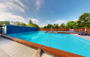 Piscine extérieure au Skovly Camping avec transats, clôture et arbres en Région Sjælland, Danemark.