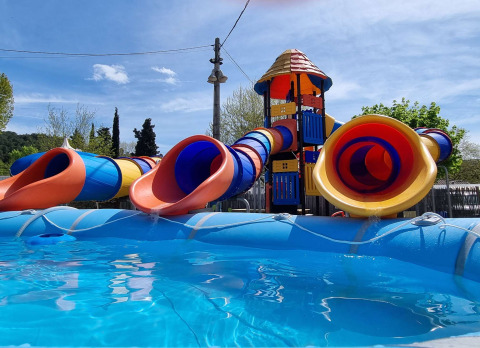 Vandlegeplads med farverige rørsklier og tårn ved pool på Camping Paradis Family des Issoux i Frankrig.