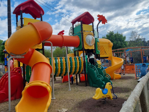 Colorful playground with tube slides and climbing tunnel at Camping Paradis Family des Issoux, France.