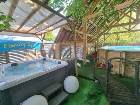 Area spa familiare con jacuzzi, piscina e vegetazione al Camping Paradis Family des Issoux, in Francia.