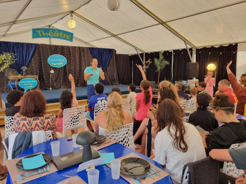 Enfants et adultes participent à une activité dans l’espace théâtre du Camping Paradis Family des Issoux, France.