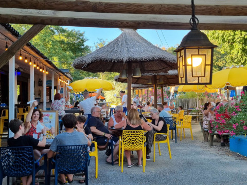 Udendørs restaurantområde på Camping Paradis Family des Issoux, Frankrig, med familier under parasoller.