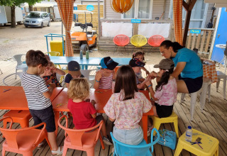 Bambini svolgono un'attività creativa di gruppo a un tavolo al Camping Paradis Family des Issoux, Francia.