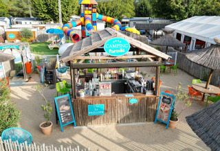 Camping Paradis Family des Issoux med farverige vandrutsjebaner, udendørs café og stråtækte parasoller.