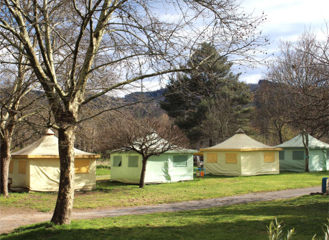 Eco-friendly Ecotent Lodge safari tents at Camping Paradis Family des Issoux, France, amid leafy trees.