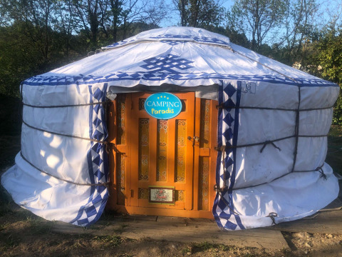 Una yurta tradizionale mongola con porta arancione decorata al Camping Paradis in Auvergne-Rhône-Alpes, Francia.