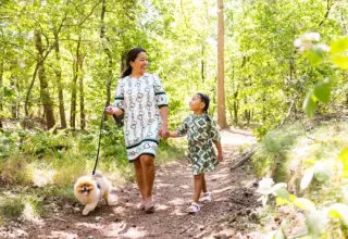 Madre e hija caminan de la mano con su perro por un sendero soleado en Holiday park «Latour», Brabante Septentrional.