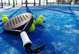 Padel racket and balls on a blue court in Holiday park Latour, North-Brabant, Netherlands, in sunlight.