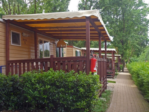 Reeks mobiele lodges met overdekte veranda’s bij SunLodge Aspen, Altomincio Family Park in Italië, groenrijk.