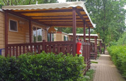 Mobil-lodges avec véranda couverte à SunLodge Aspen, Altomincio Family Park en Italie, entourés de verdure.