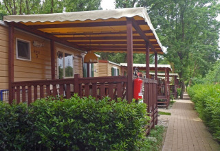 Mobil-lodges avec véranda couverte à SunLodge Aspen, Altomincio Family Park en Italie, entourés de verdure.
