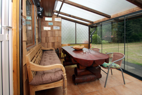 Véranda lumineuse avec mobilier en bois et vue sur le jardin à Holiday home «Susanne 58 qm» en Allemagne.