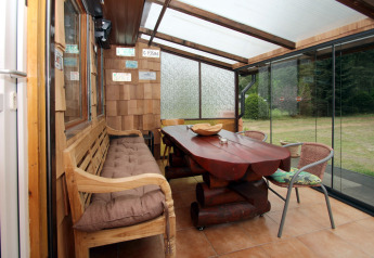 Luminoso porche acristalado con muebles de madera y vistas al jardín en Holiday home «Susanne 58 qm» en Alemania.