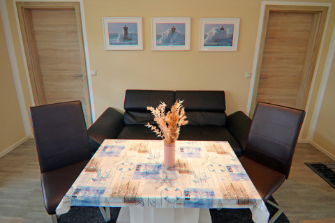 Woonruimte in de lodge Am Strand in Duitsland met zwarte bank, tafel en maritieme decoratie.