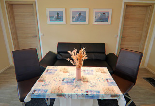 Woonruimte in de lodge Am Strand in Duitsland met zwarte bank, tafel en maritieme decoratie.