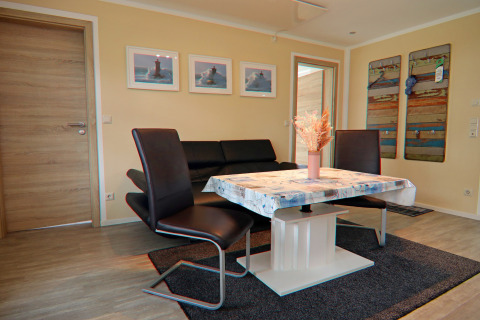 Woonkamer in lodge 'Am Strand' in Duitsland met moderne meubels, wanddecoratie en veel licht.