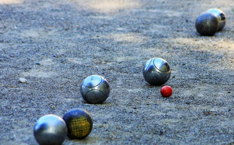 Metalen ballen en een klein rood balletje op grind, gefotografeerd in Arden Parks Tulderheyde, Antwerpen.