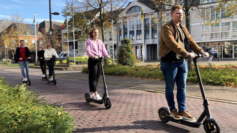 Een groep jonge mensen rijdt met elektrische steps op een zonnige dag bij Arden Parks Tulderheyde, Antwerpen.