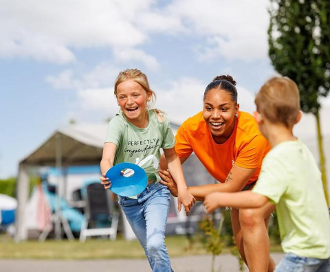Zwei Kinder und ein Erwachsener spielen draußen im Ferienpark Arden Parks Tulderheyde in Antwerpen, Belgien.