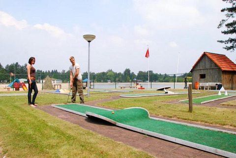 Due persone giocano a mini golf vicino a un lago ad Arden Parks Tulderheyde, parco vacanze ad Anversa, Belgio.