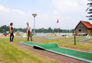 Twee mensen spelen minigolf aan een meer in Arden Parks Tulderheyde vakantiepark, Antwerpen, België.