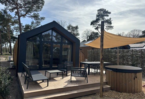 Hyggelig Boslodge med moderne terrasse, udendørs siddepladser, overdække, sauna og træ-hot tub i naturen.