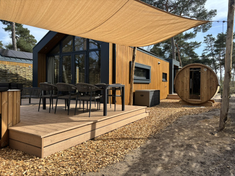 Terrasse extérieure de Boslodge avec sièges, bain à remous et sauna rond, entourée de forêt et nature.