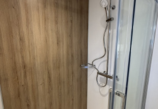 Photo d'une douche moderne dans une tiny house, avec paroi effet bois et porte en verre.