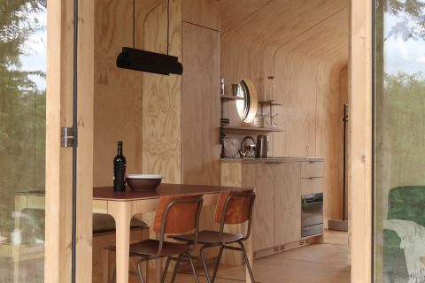 Moderne, træbeklædt lodge-interiør med køkken og spisebord på Wikkelhouse met Ligbad, Resort de Parel.