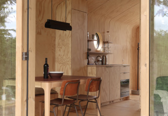 Modern wood-paneled lodge interior with kitchen and dining table at Wikkelhouse met Ligbad, Resort de Parel.
