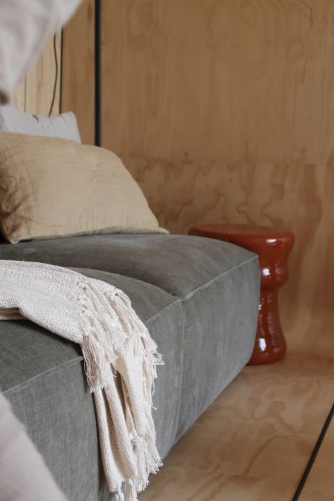 Moderne lounge i Wikkelhouse med grå sofa, beige pude og tæppe på Resort de Parel, Holland.