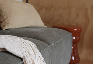 Moderne lounge i Wikkelhouse med grå sofa, beige pude og tæppe på Resort de Parel, Holland.