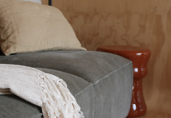Modern cozy corner in Wikkelhouse featuring grey couch, cushions and throw blanket at Resort de Parel, Netherlands.