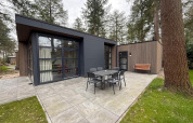 Outdoor patio at the L-Cube lodge in De Utrechtse Heuvelrug, Netherlands, featuring table, chairs, and bench.
