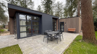 Udendørs terrasse ved L-Cube lodge på De Utrechtse Heuvelrug i Holland, med bord, stole og bænk.