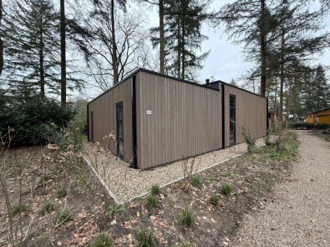 Lodge genaamd L-Cube op De Utrechtse Heuvelrug, Nederland, omringd door bomen en een grindpad.