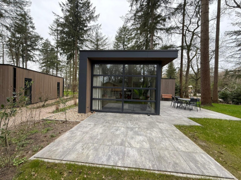 L-Cube lodge in De Utrechtse Heuvelrug, Nederland, met grote glaspartijen en betegeld terras.