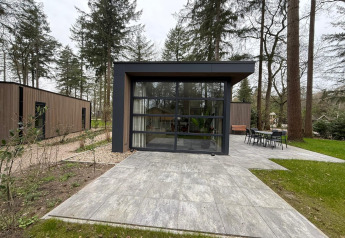 Moderna cabaña L-Cube en De Utrechtse Heuvelrug, Países Bajos, con grandes ventanas y terraza exterior.