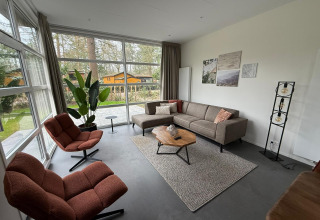 Woonruimte in de L-Cube lodge op De Utrechtse Heuvelrug, Nederland, met grote ramen en moderne inrichting.