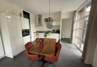 Moderne eethoek en keuken in de L-Cube lodge bij De Utrechtse Heuvelrug, Nederland, met grote raampartijen.