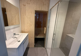 Baño moderno con lavabo, ducha de cristal y puerta de sauna de madera en L-Cube, Utrechtse Heuvelrug, Países Bajos.
