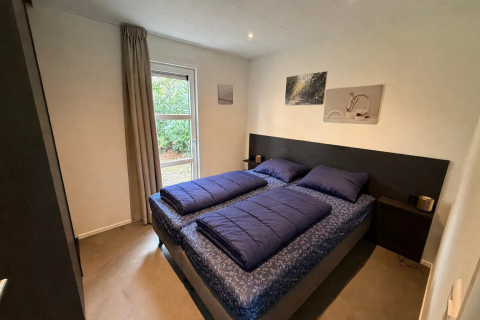 Moderne slaapkamer in de L-Cube-lodge bij De Utrechtse Heuvelrug, Nederland, met twee enkele bedden.