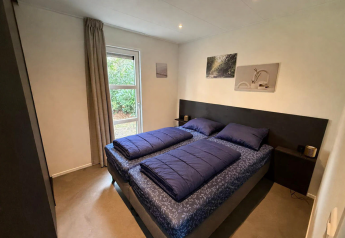 Dormitorio moderno en la cabaña L-Cube en De Utrechtse Heuvelrug, Países Bajos, con dos camas individuales.