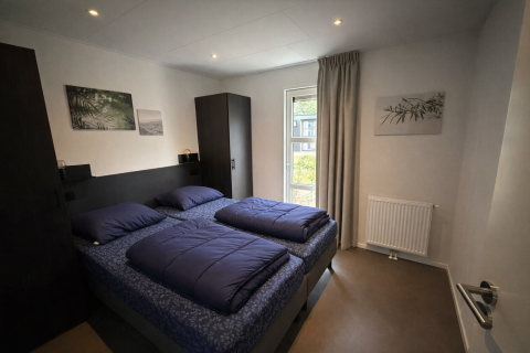 Moderne slaapkamer in de L-Cube lodge bij De Utrechtse Heuvelrug, met twee bedden en minimalistische inrichting.